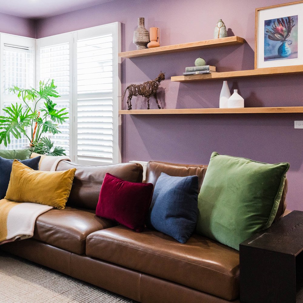 Leather sofa, mauve walls and colourful cushions