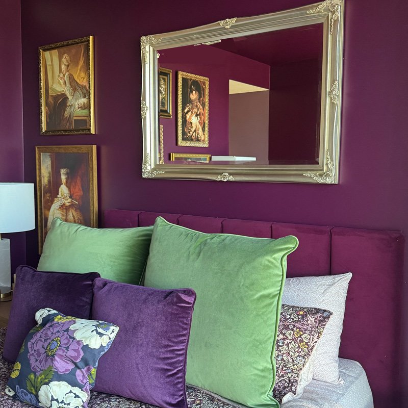 Plum coloured walls, rich cherry velvet bedhead and gilded mirror