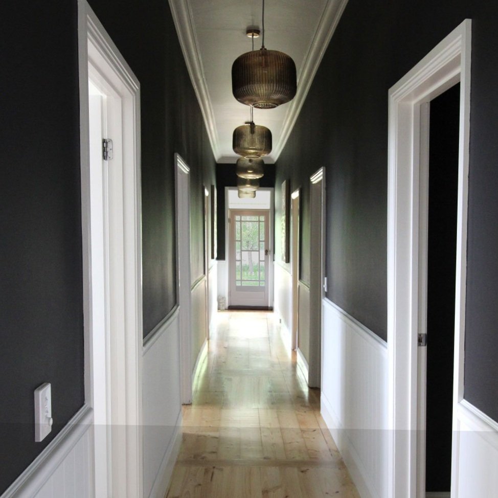 Hallway with the lights off, dark walls and white paneling designed by Hue and Space Interior Design