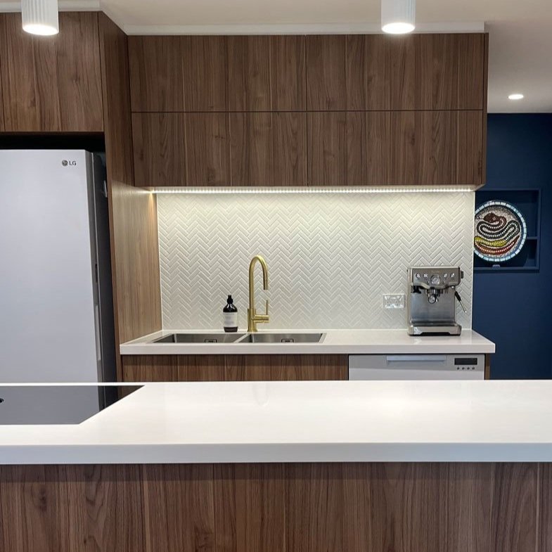 Kitchen designed with simple white herringbone tile and timber cabinets designed by Hue and Space