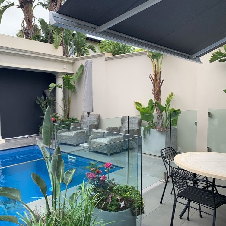 Outdoor awning extended over patio table and chair by a pool