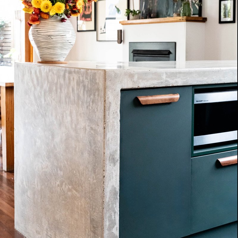 showing the concrete waterfall counter of a green kitchen