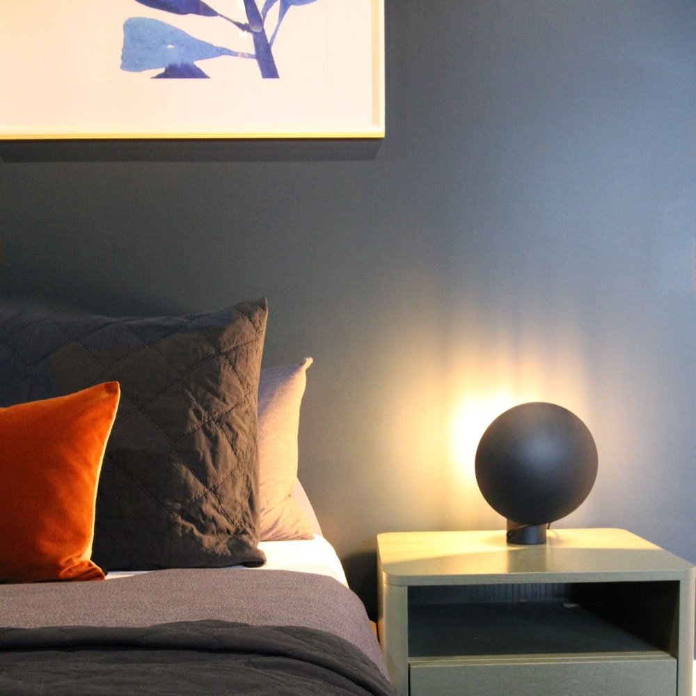 Boys bedroom, bed with dark blue walls, green side table, terracotta velvet cushion and black lamp designed by Hue and Space Interior design melbourne