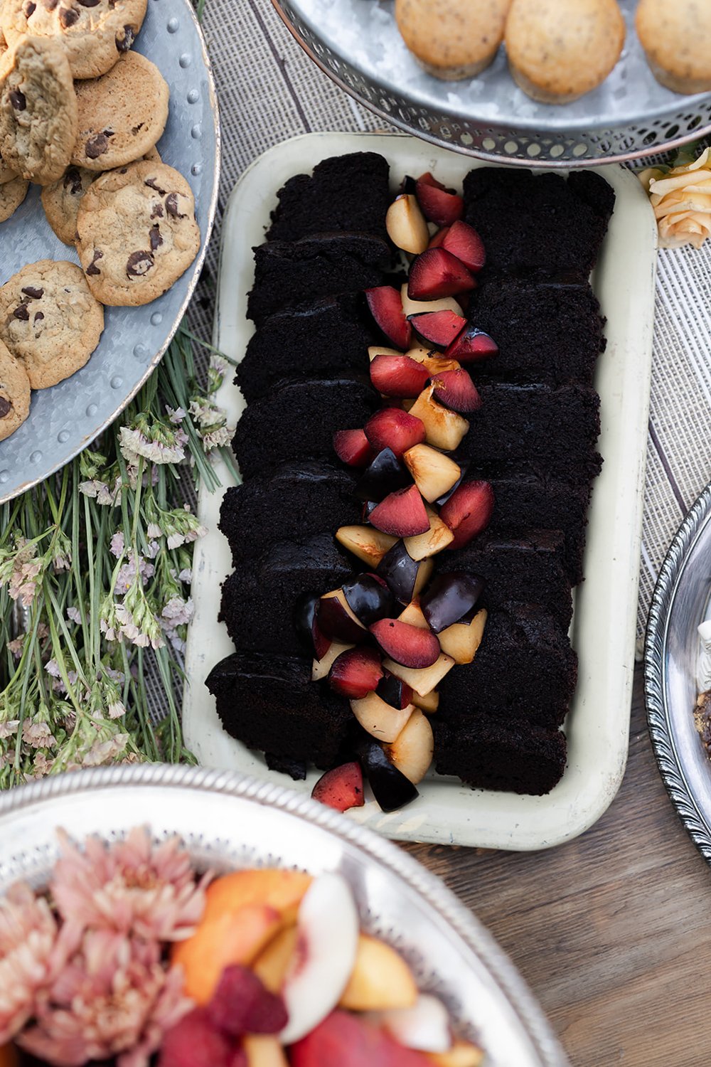 rich chocolate brownies served with stone fruits on dessert table at wedding