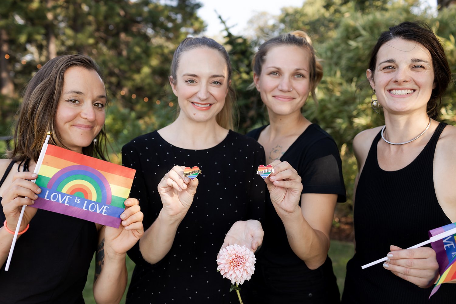 group of women smiling with love is love rainbow flags to support portland oregon lgbtq+
