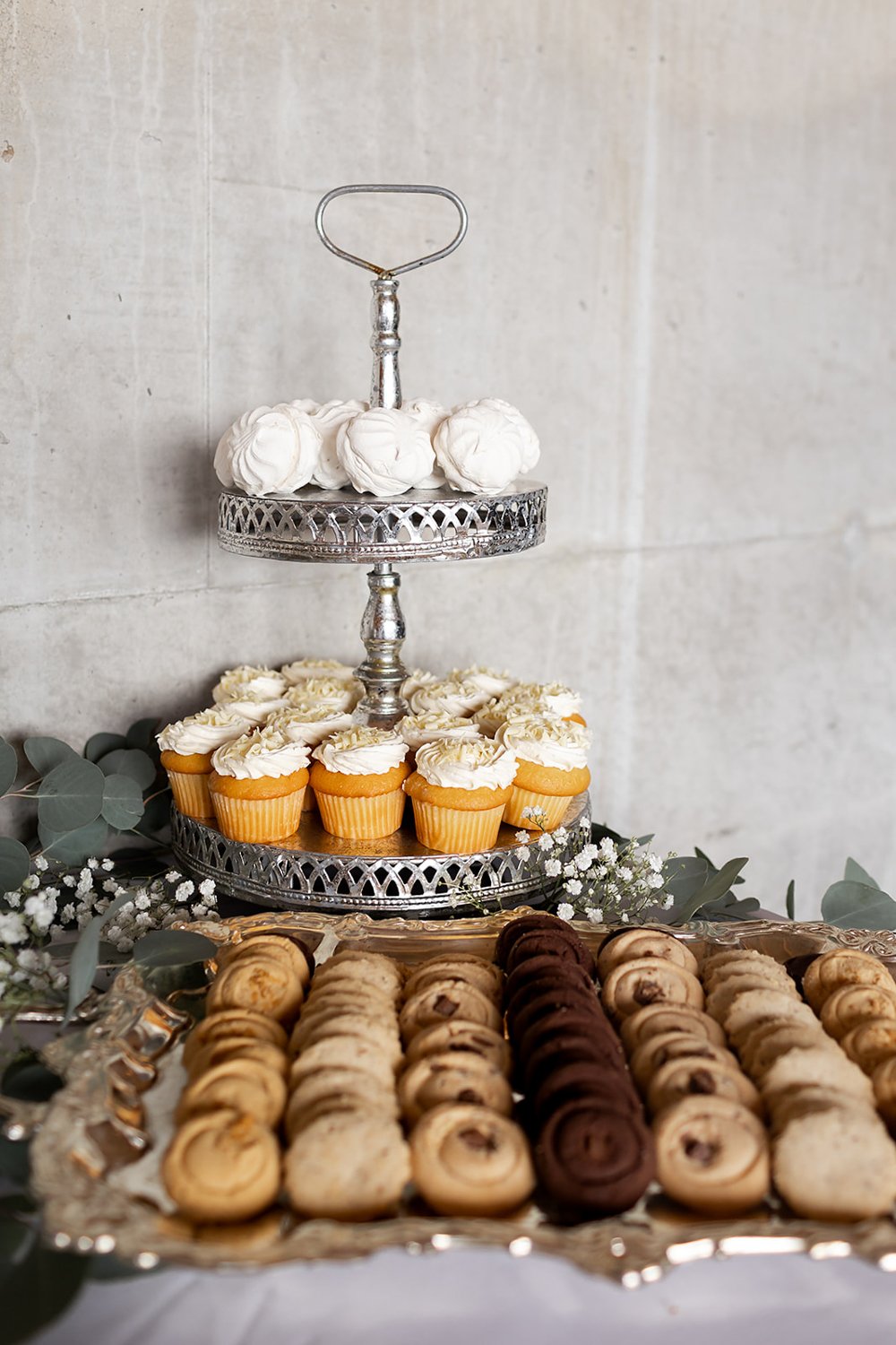 cookies and cupcakes on display for after dinner wedding dessert