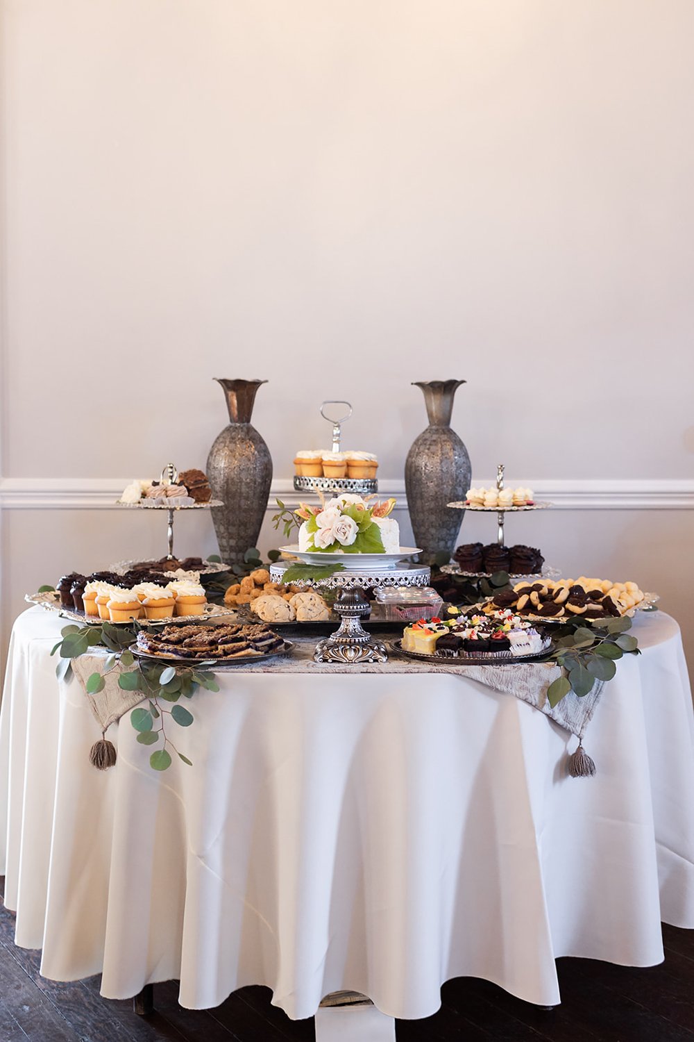 small dessert bar with cupcakes cookies and cakes at wedding 