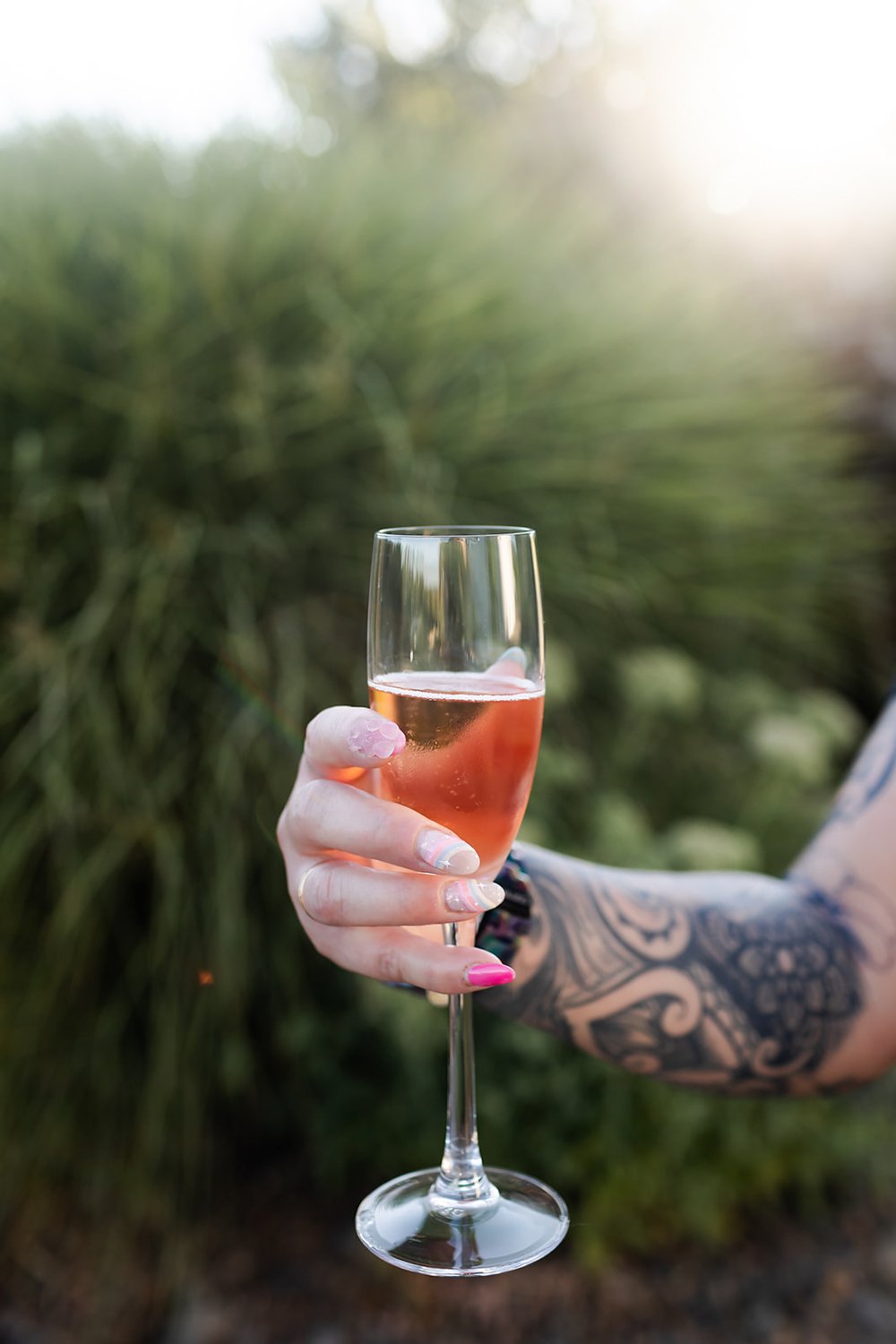 woman's hand holding a glass of sparkling rose at a wedding