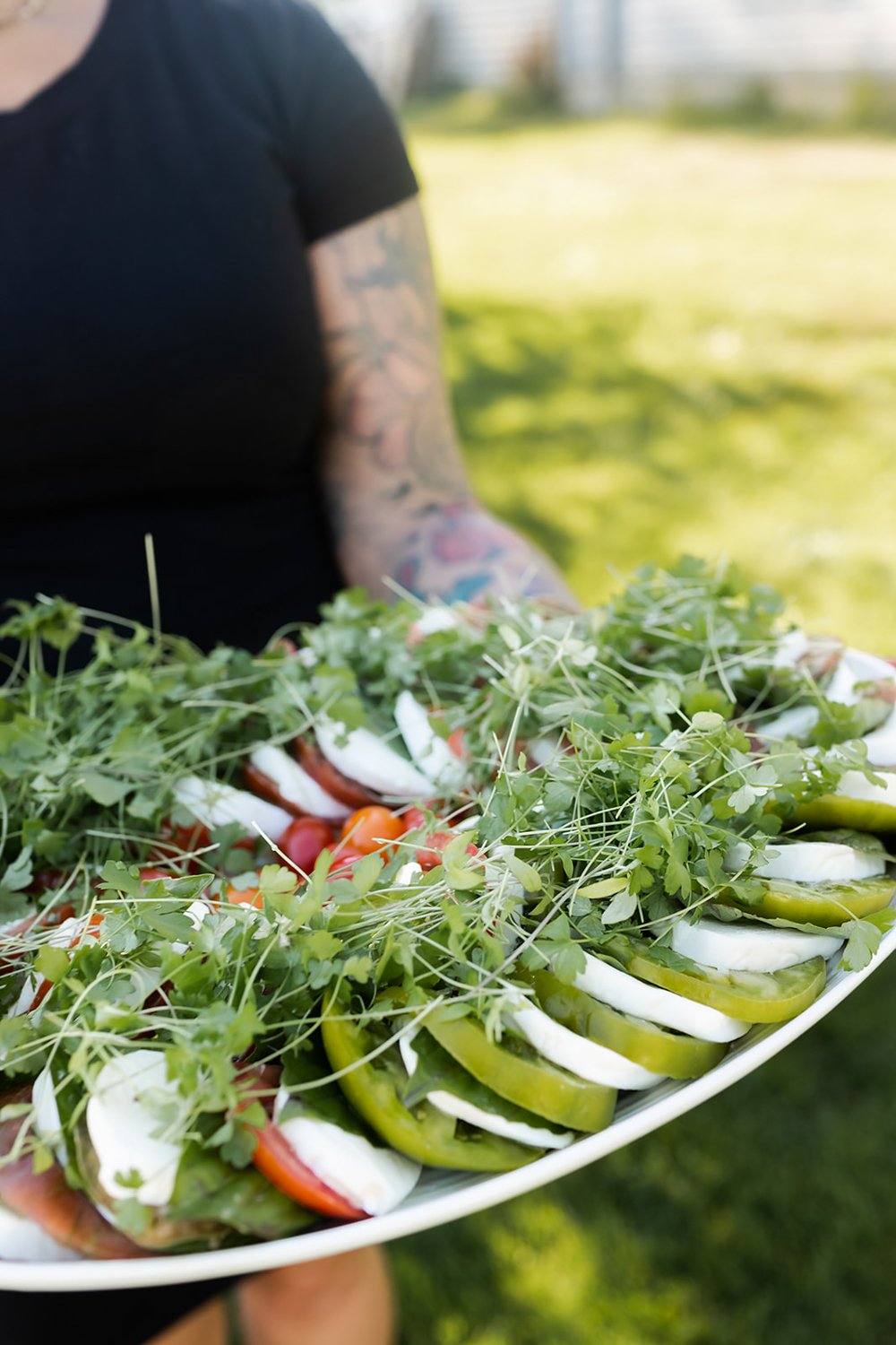 catering employee holding large tray of caprese salad for wedding event in portland