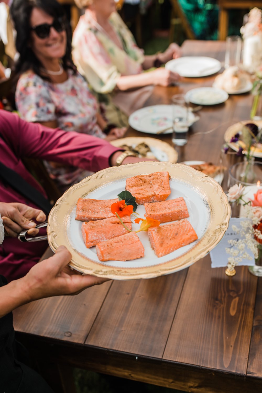fresh salmon being passed around at family style table during wedding in portland oregon