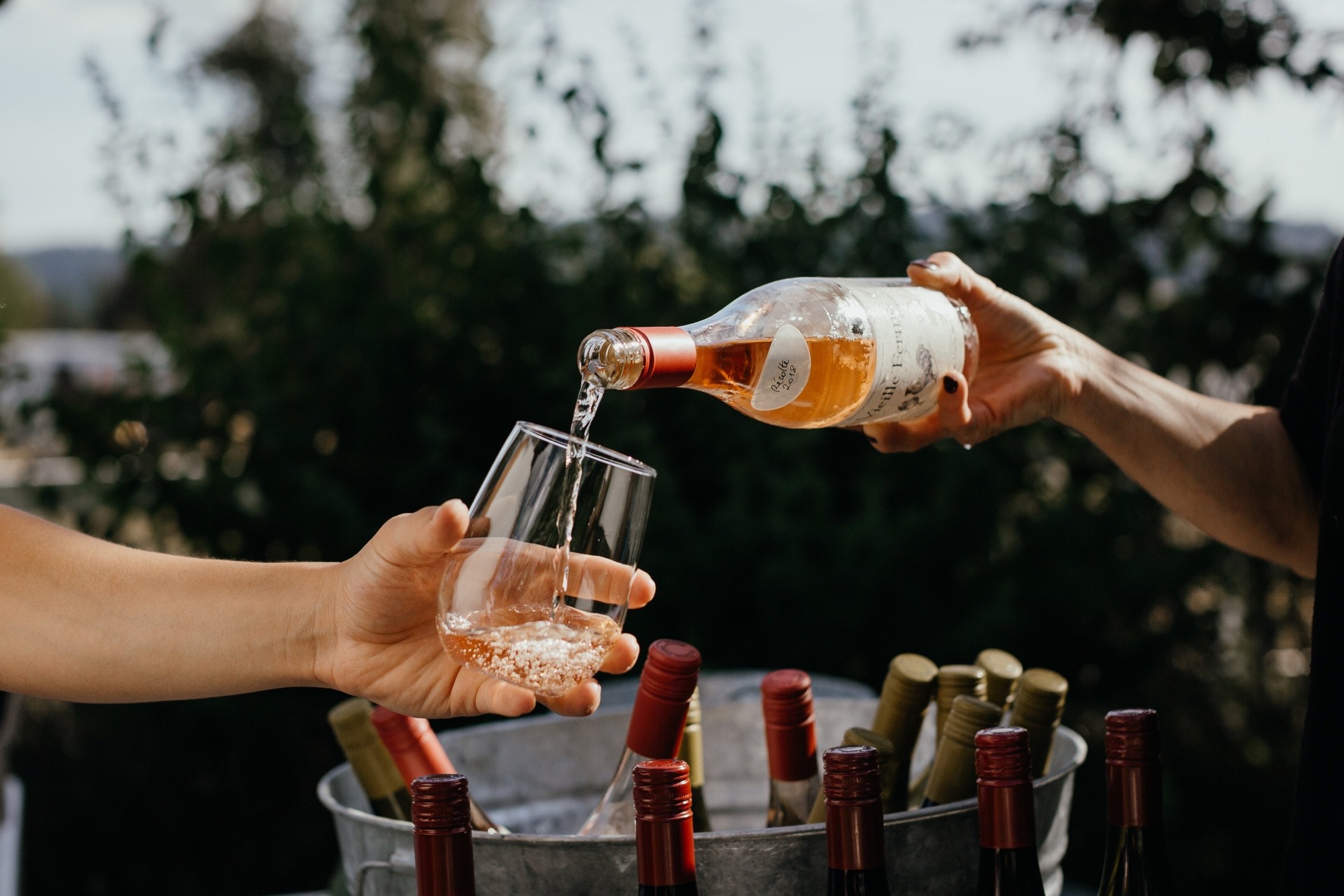 bartender pouring la vielle ferme rose into wine glass at outdoor wedding