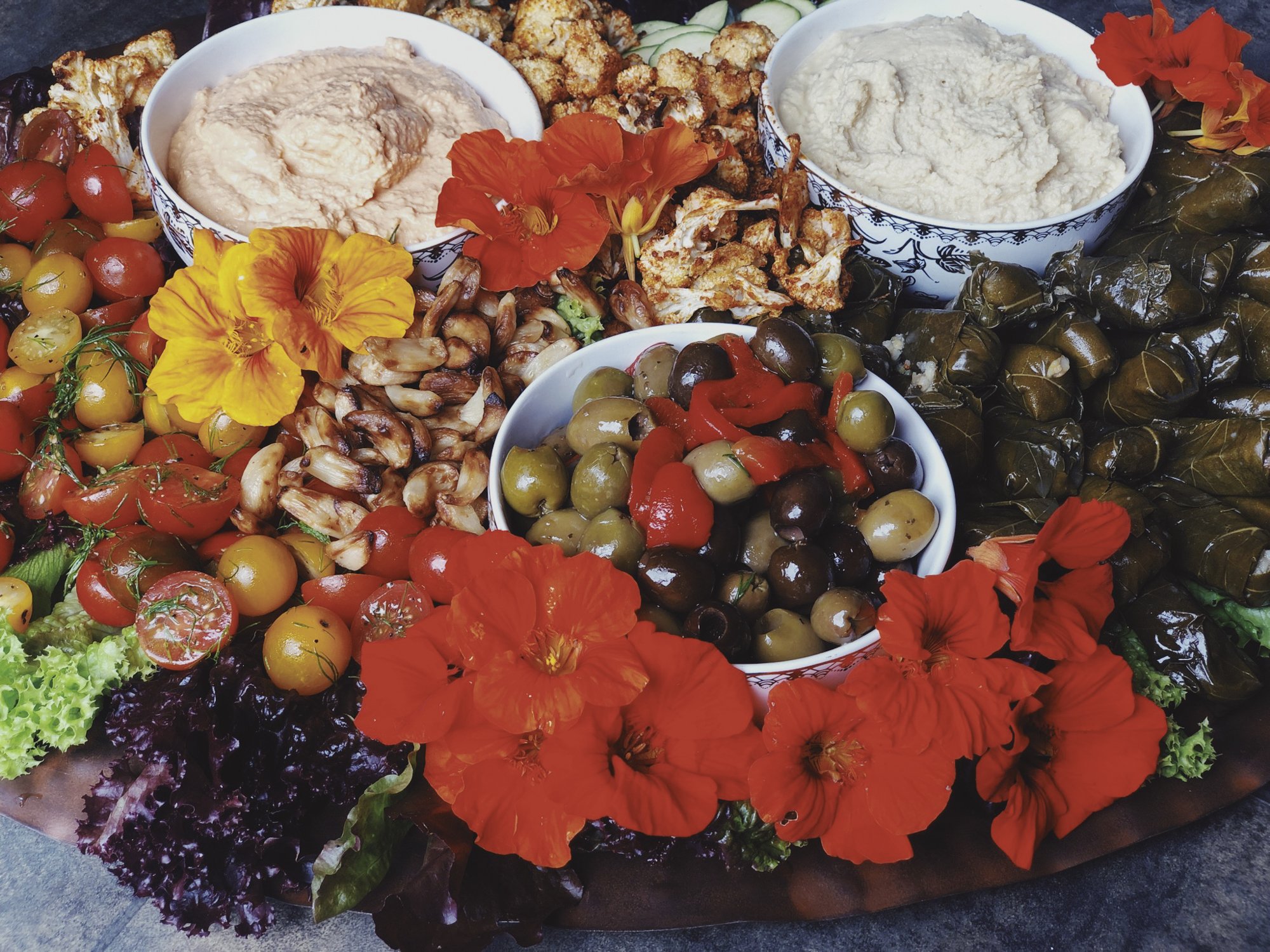 vegetable platter with hummus, dip, olives and edible flowers