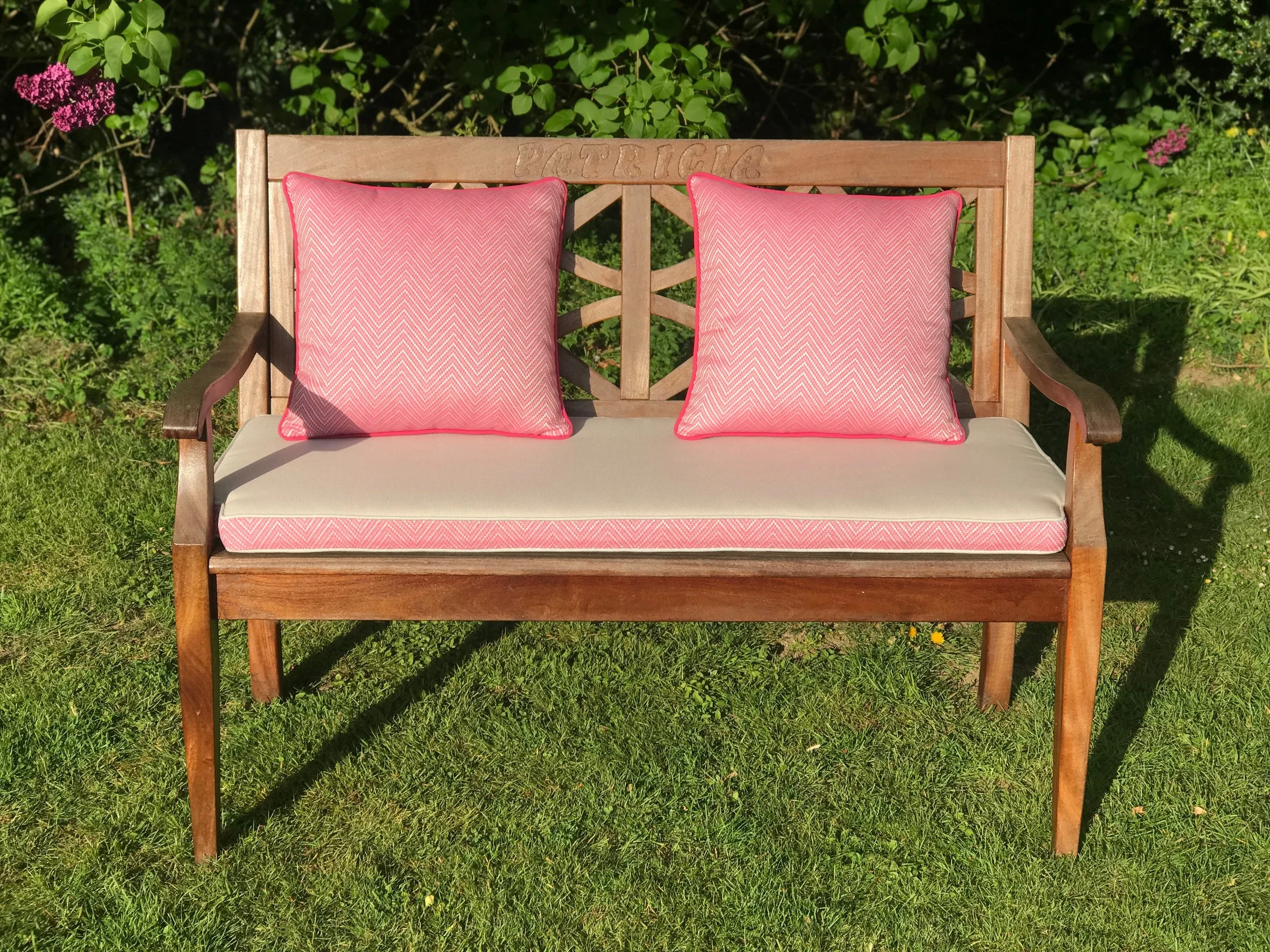 Bench cushion with pink feather border and pink feather scatters