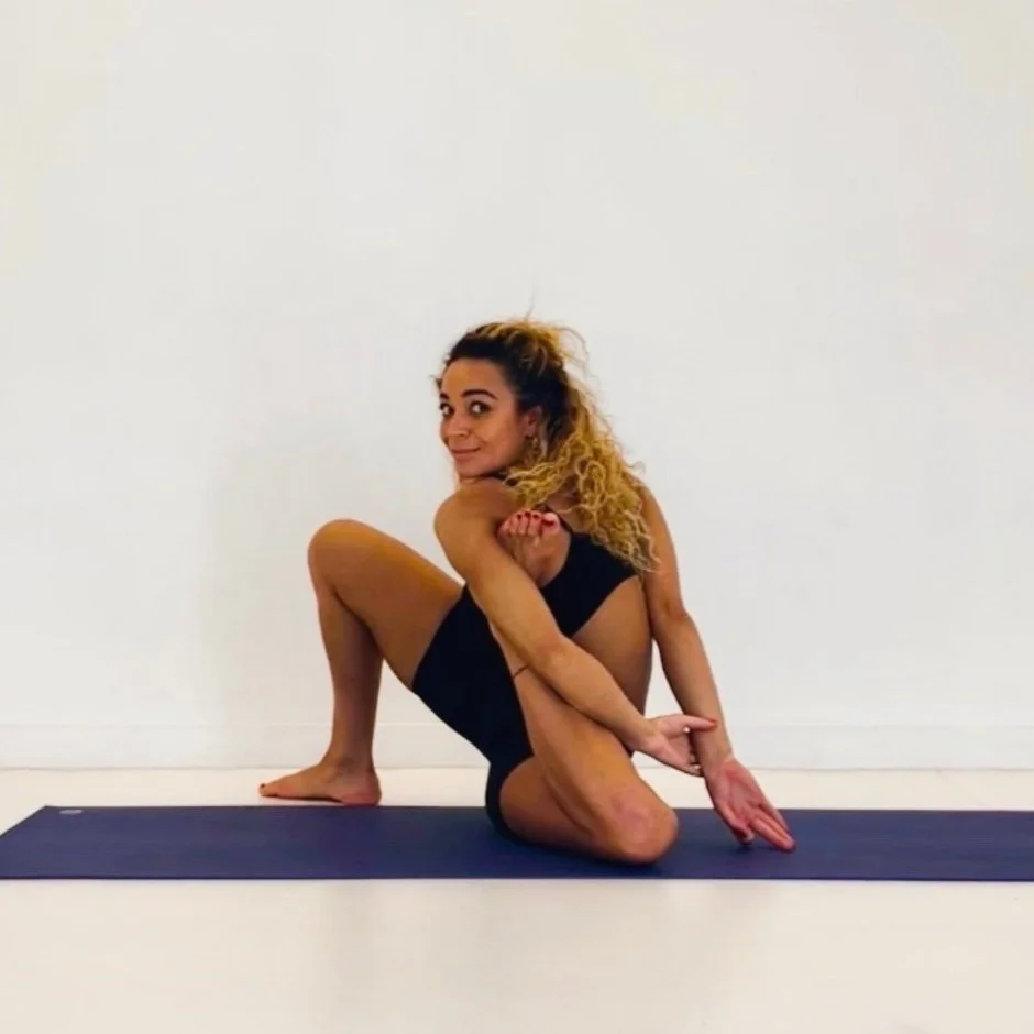 Emily Harding standing in a matching Vuori turqouise yoga set, with hands on hips and beaming at the camera