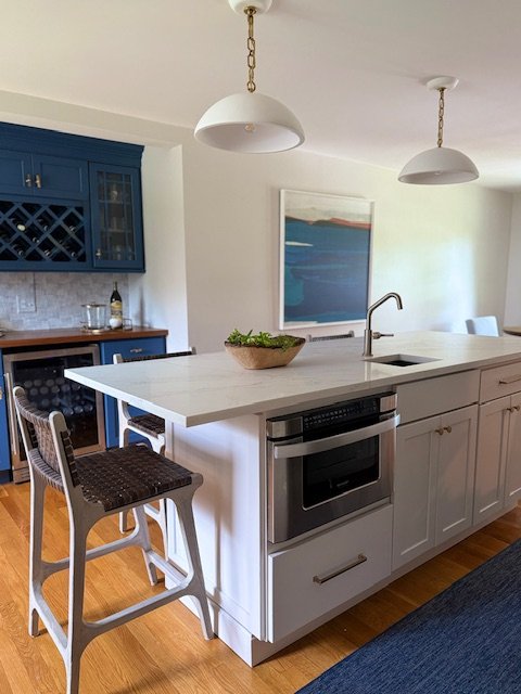 Modern kitchen with white island, blue cabinets, and wooden floor.