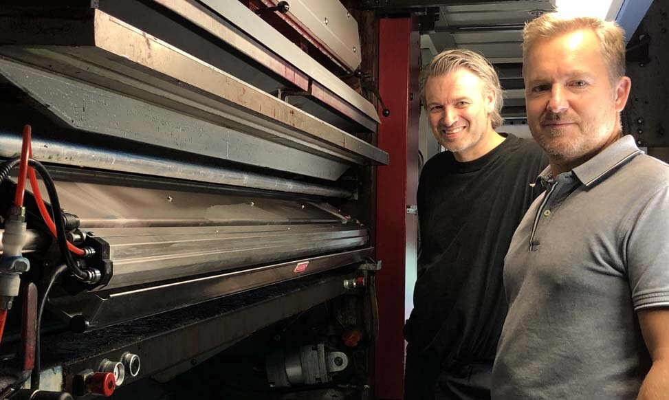 印刷操作员Kim Fuglsang Kristiansen（左）和技术经理Niels Anker Priebe Kragh在Baldwin公司的EvenSpray World2前。