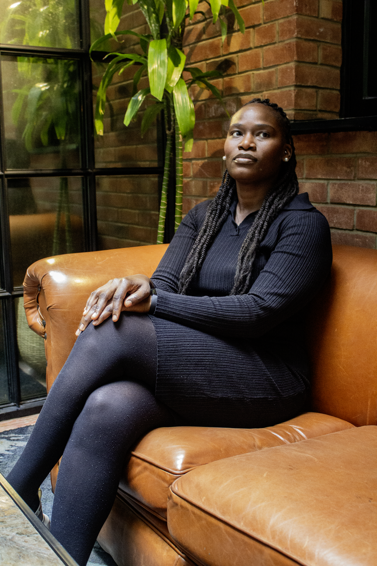 A female founder wearing all black sits on a leather sofa