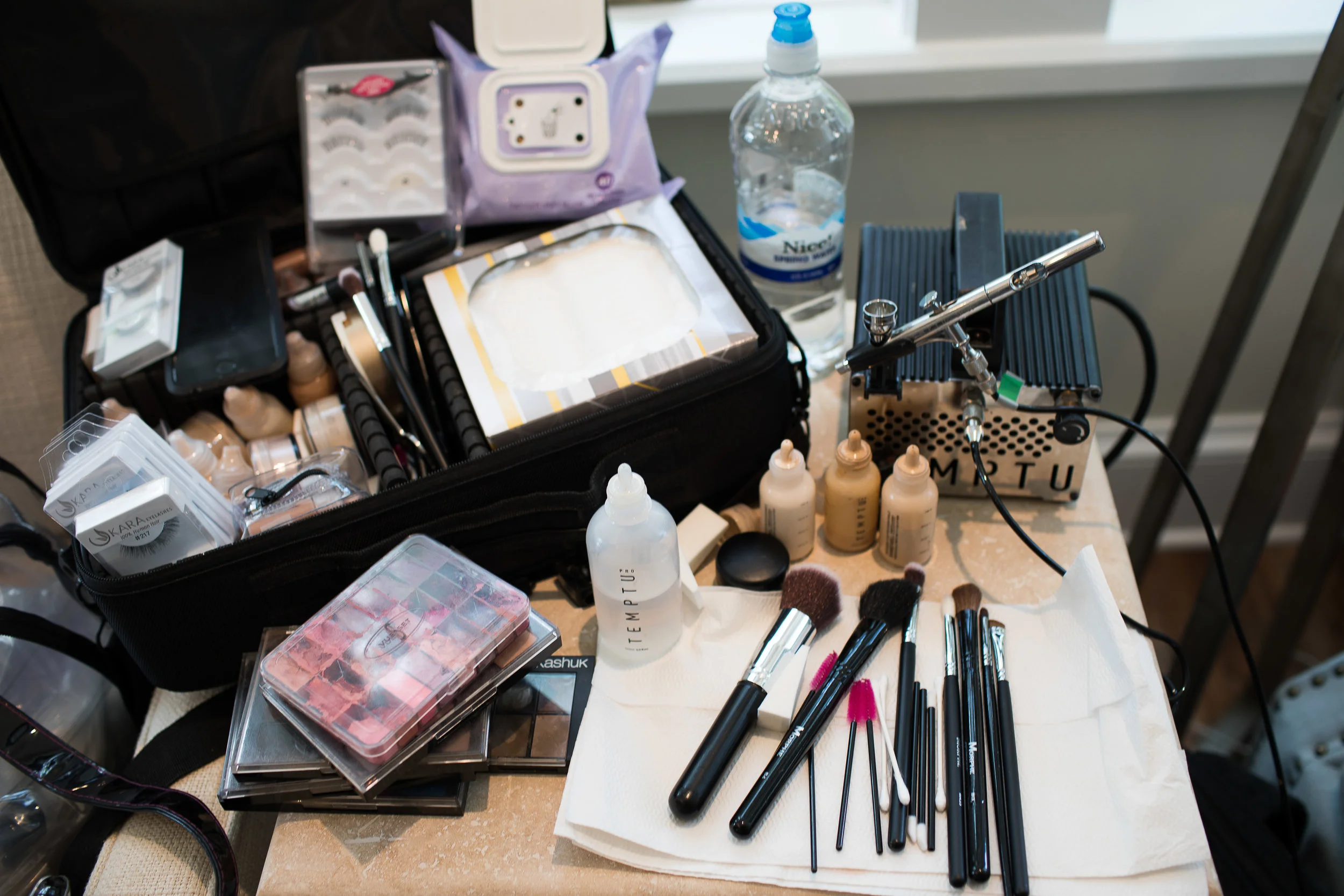 Cosmetics and airbrush foundation laid out for beauty session on site