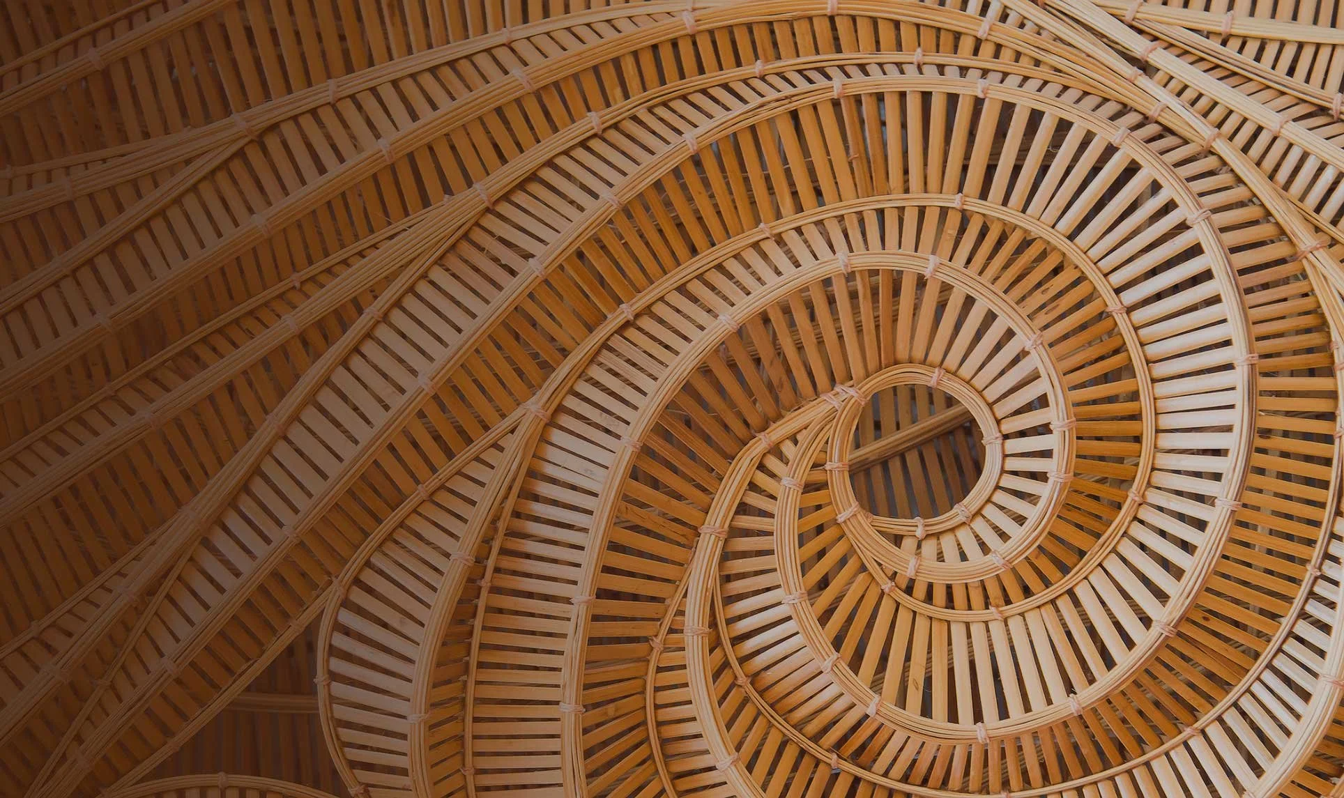 Close-up of a wooden spiral staircase, showcasing the intricately woven wooden slats and curved design from above.