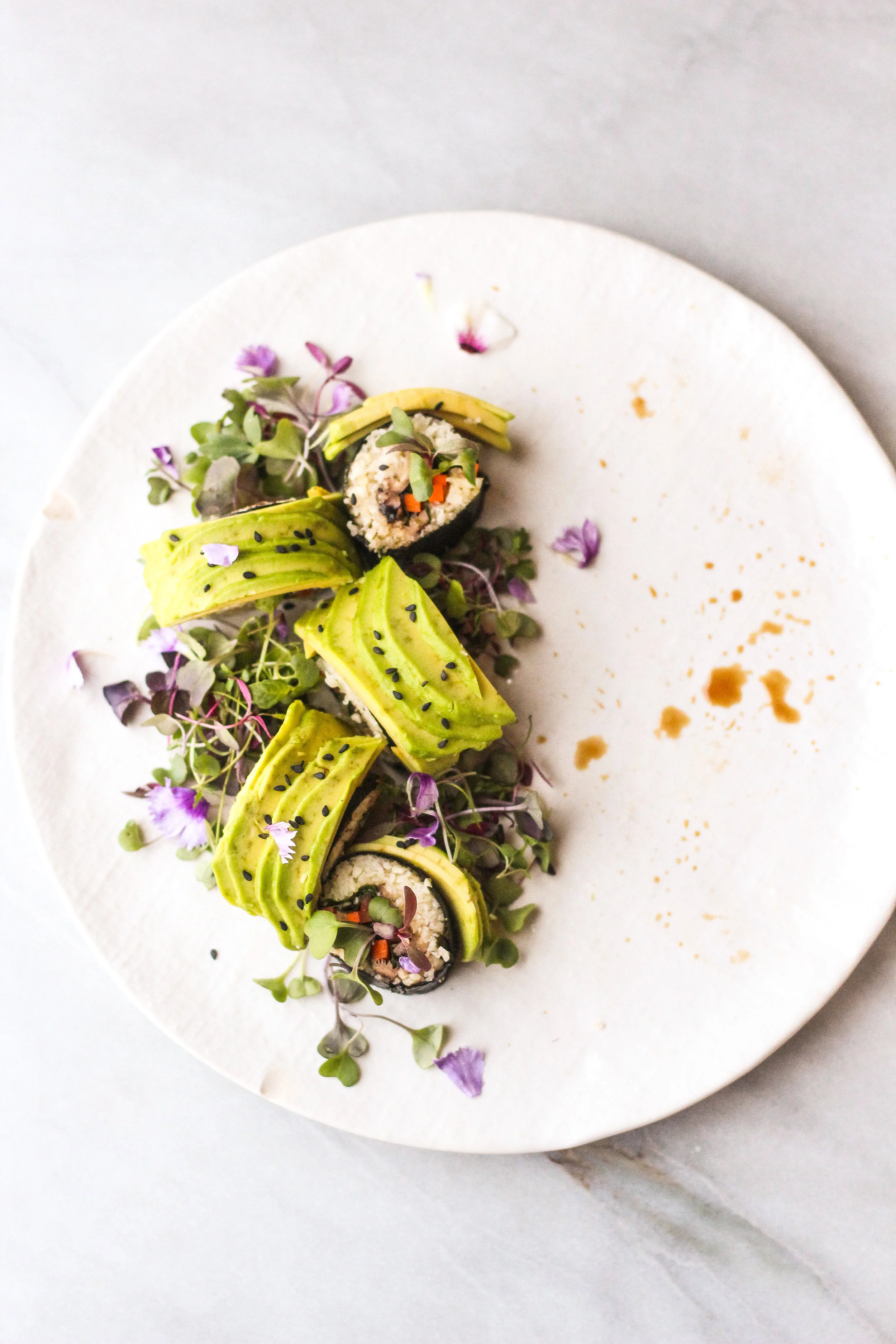Cauliflower sushi with carrots, tamari mushrooms and avocado on a bed of arugula and radish sprouts.
