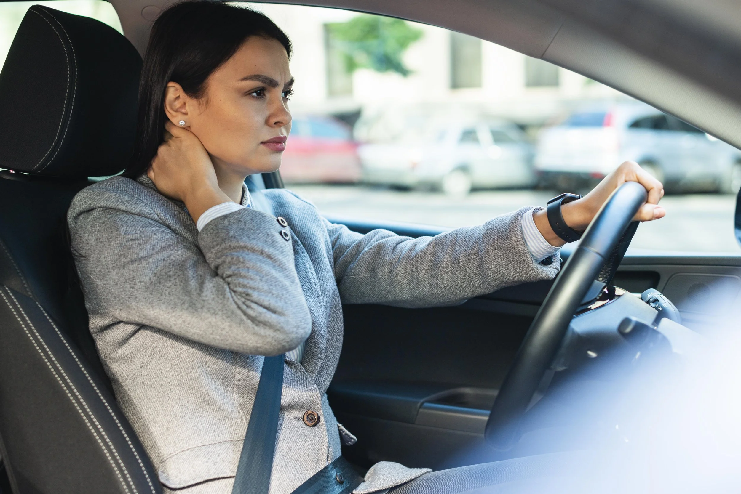 Woman driving in her car experiencing neck pain and in need of a Norman car accident doctor