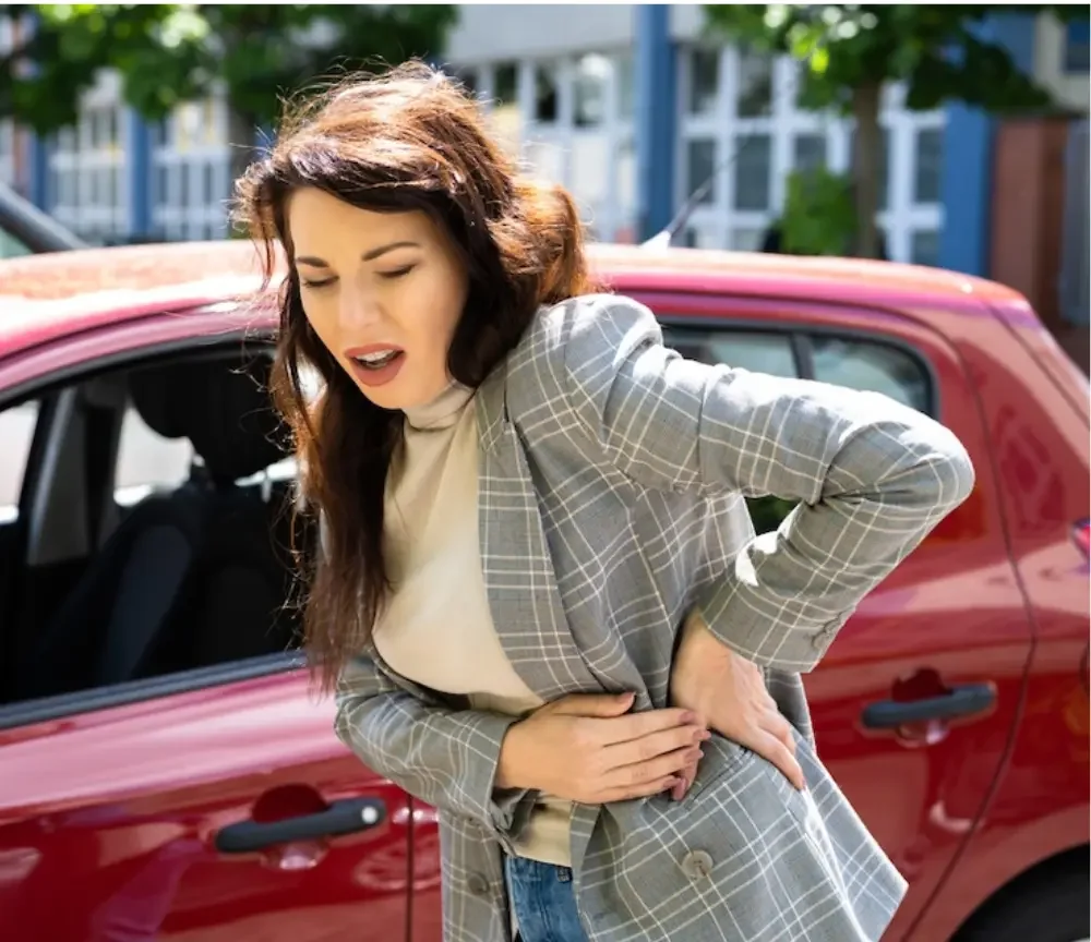 Car accident doctor the greens oklahoma city - woman holding her back in pain next to car after a collision