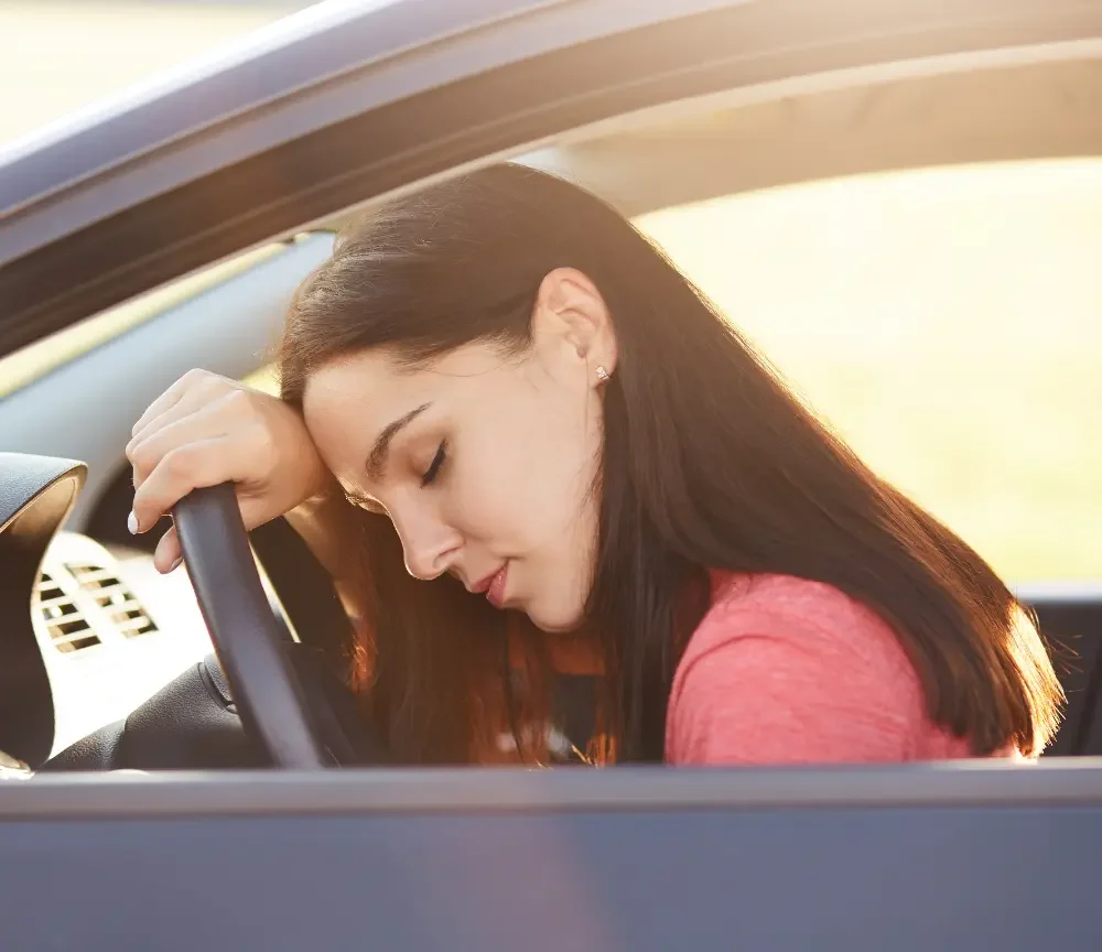 Woman leaning her head against the wheel of a car after an injury in need of a car accident doctor in Midtown OKC