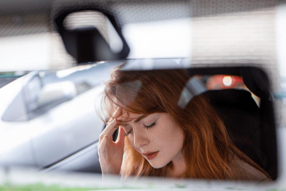 Woman in car rubbing forehead in pain in need of a car accident doctor in Belle Isle Oklahoma City