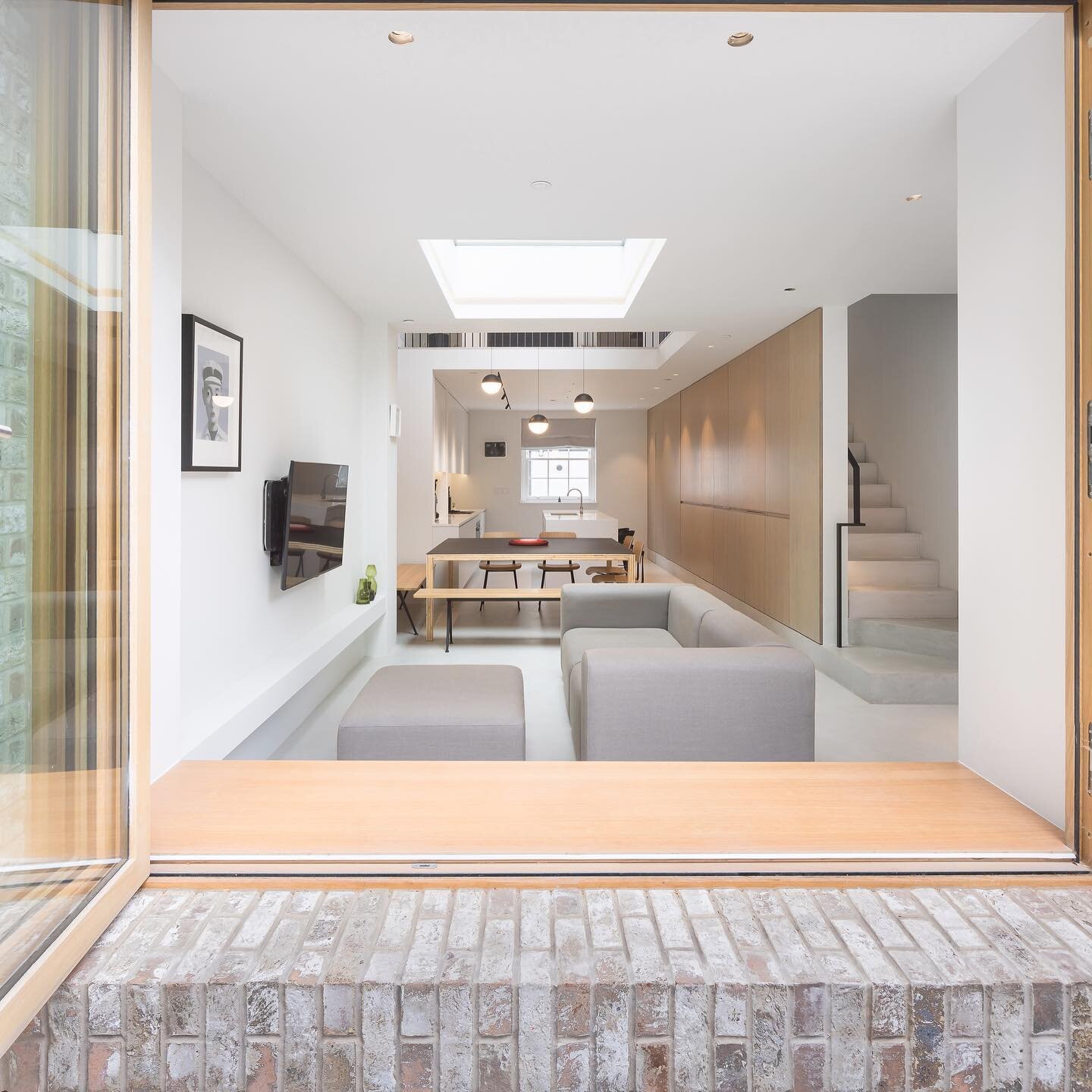 Bifolding door / Bench seat : Islington Town House. 

By forming a deep reveal for the bi fold doors, a bench seat is formed, which can be used when doors are open or closed. This is mirrored by a concrete bench opposite, which allows the owner to pl