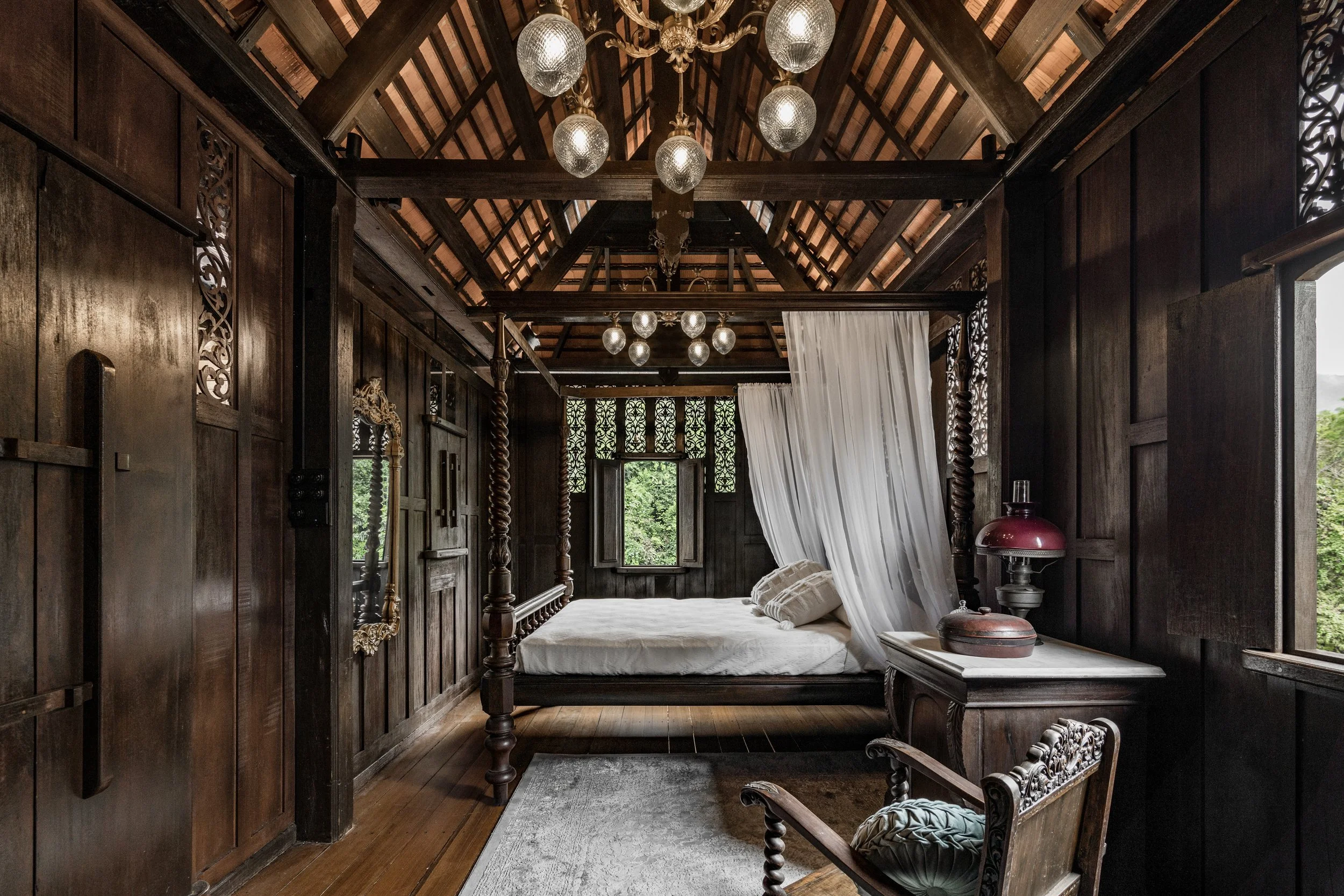  The soft sunlight picks up the intricate details of the many wood carvings that adorn the master bedroom at Rumah Tela - an 80-year old kampung house transformed into a charming nature retreat. 