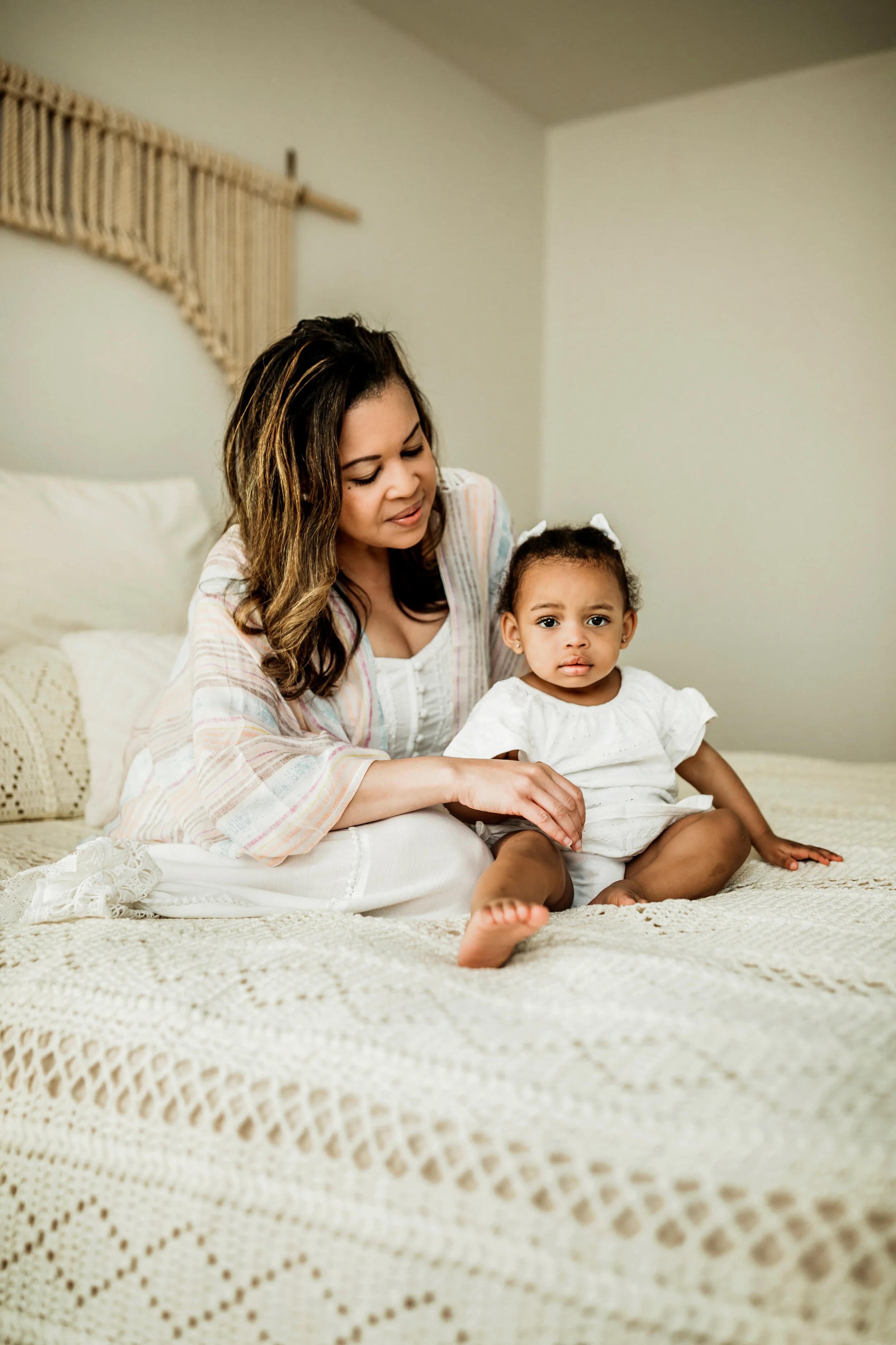 Montgomery Alabama Photographer - A mother looks down at her young daughter as they sit on a bed in Pike Road, Alabama