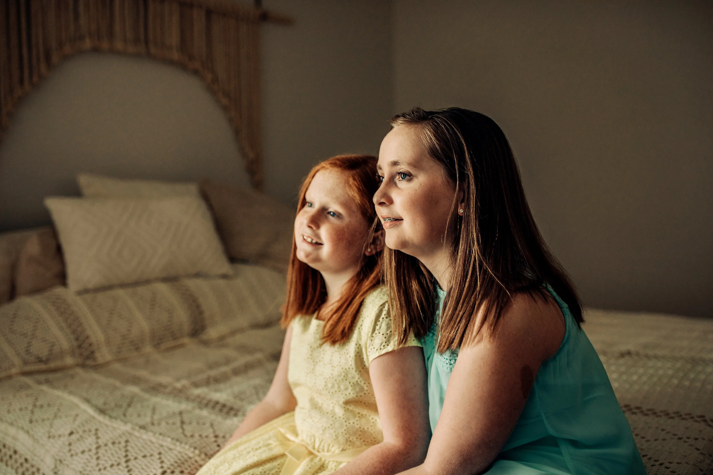 Montgomery Alabama Photographer - two sisters sit on a bed and look out a window in Pike Road, Alabama
