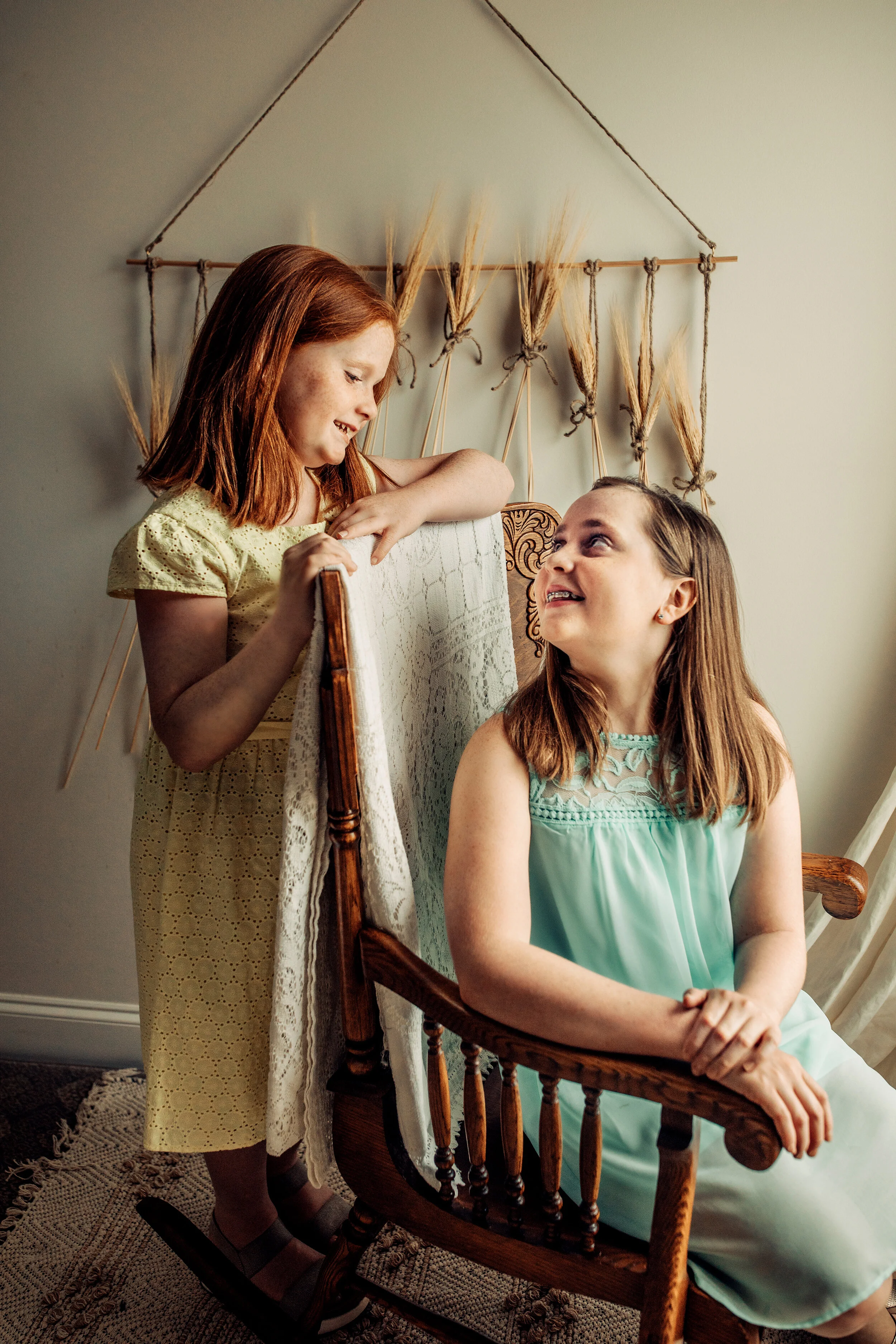 Montgomery Alabama Photographer - A girl looks down at her sister, who is sitting in a rocking chair in Pike Road, Alabama