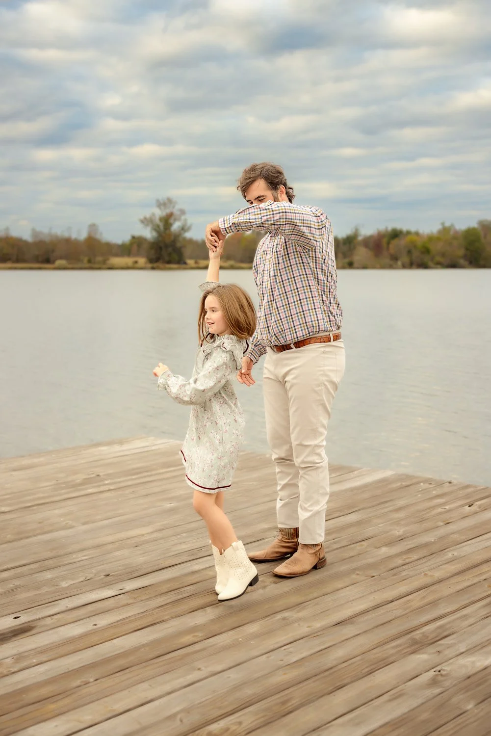 A dad dances with his young daughter on a dock in Pike Road, Alabama during a photo session with m.Clemm photography