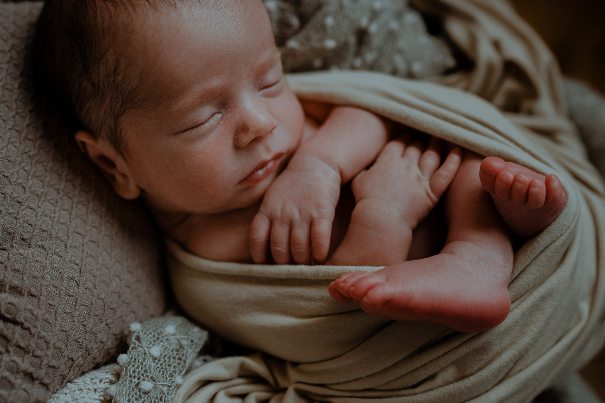 curled up newborn baby boy in neutral wrap creative newborn photographer Belfast