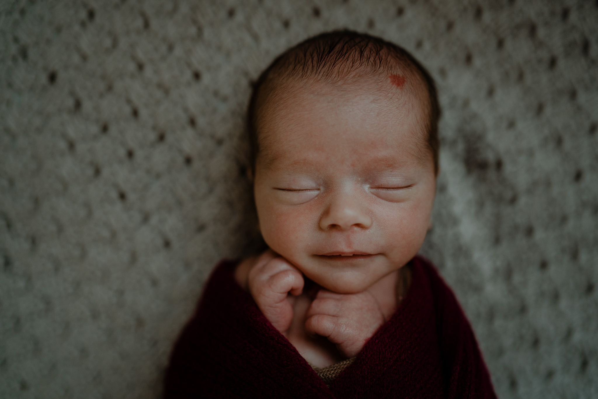 smiling Newborn baby boy in burgundy wrap twin baby photographer Belfast