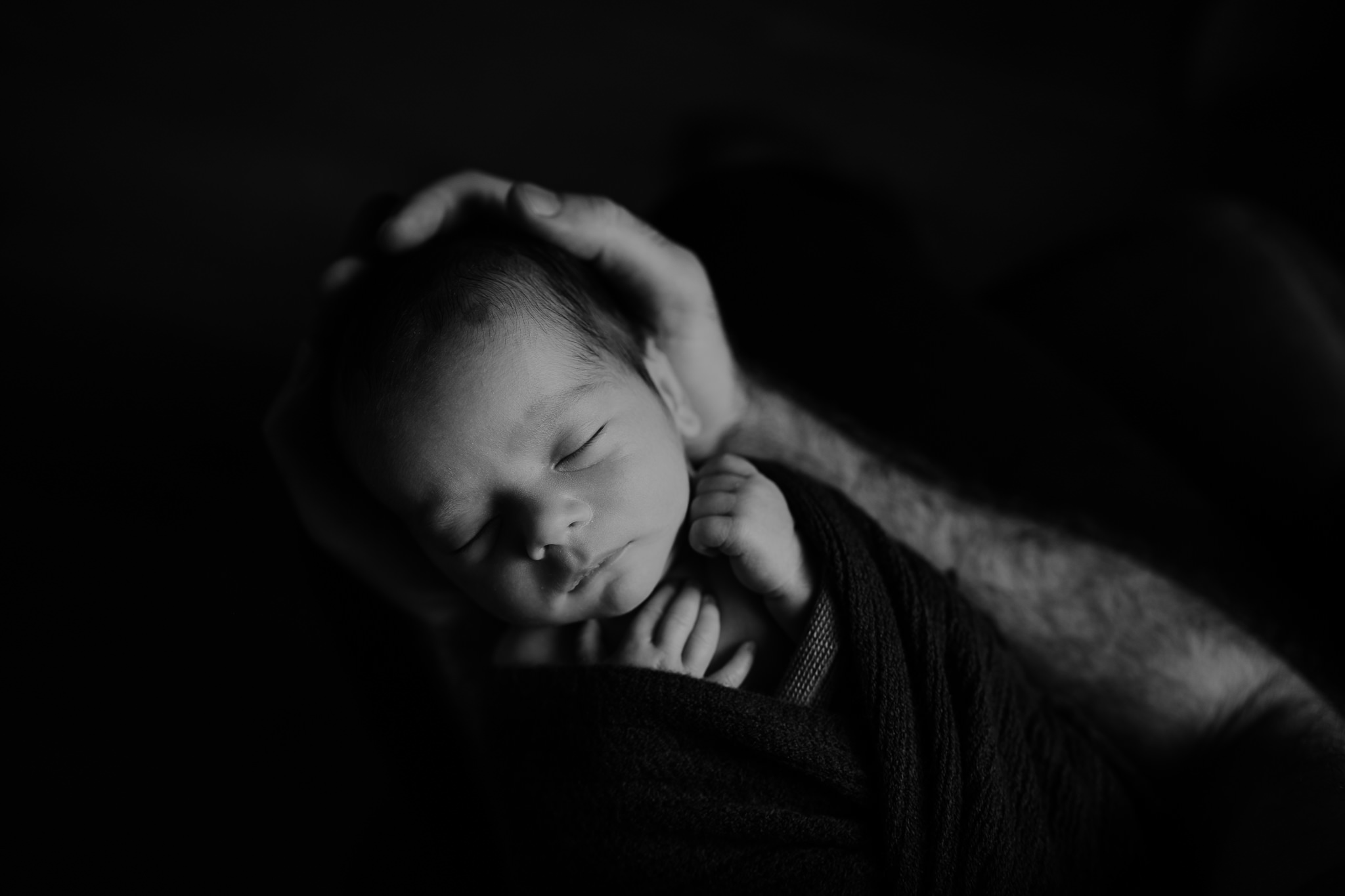 newborn baby boy in fathers arms black and white creative baby photographer Belfast