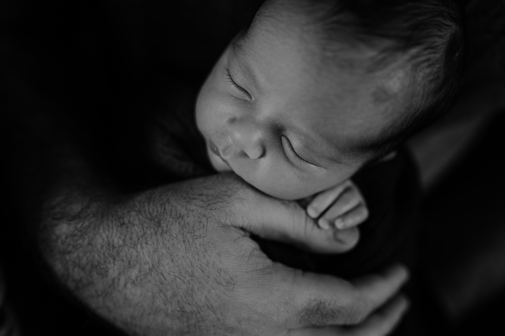 newborn boy tiny hand next to fathers hand black and white creative newborn photographer Belfast