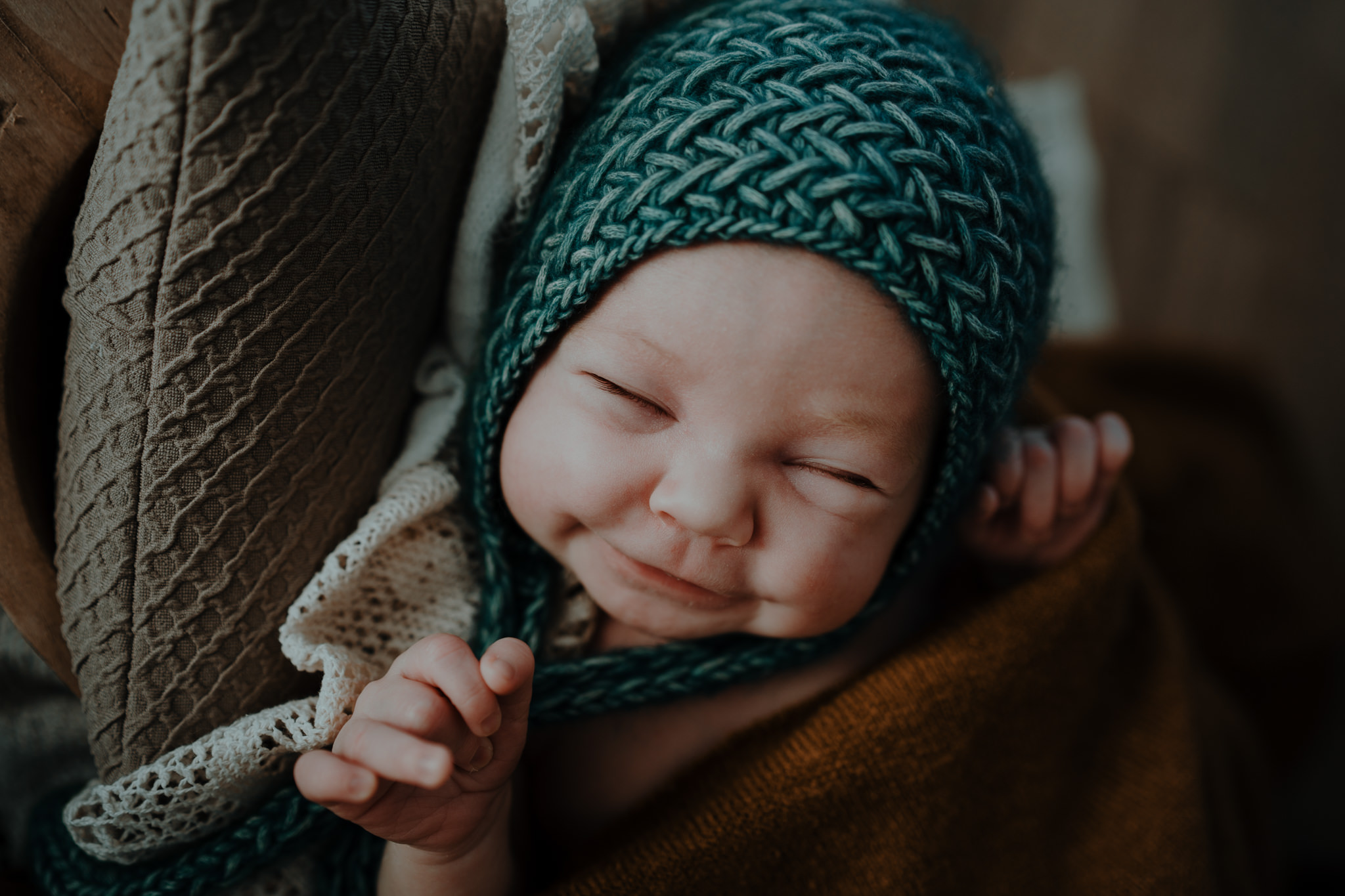 smiling newborn baby teal knit bonnet in home artistic newborn photographer belfast