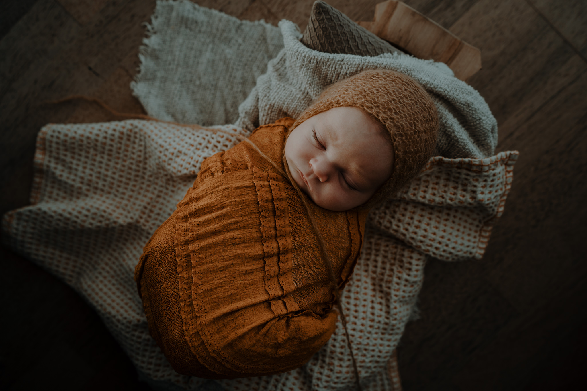 rustic mustard rust and cream styled baby in wrap and bonnet in home artistic newborn photographer belfast