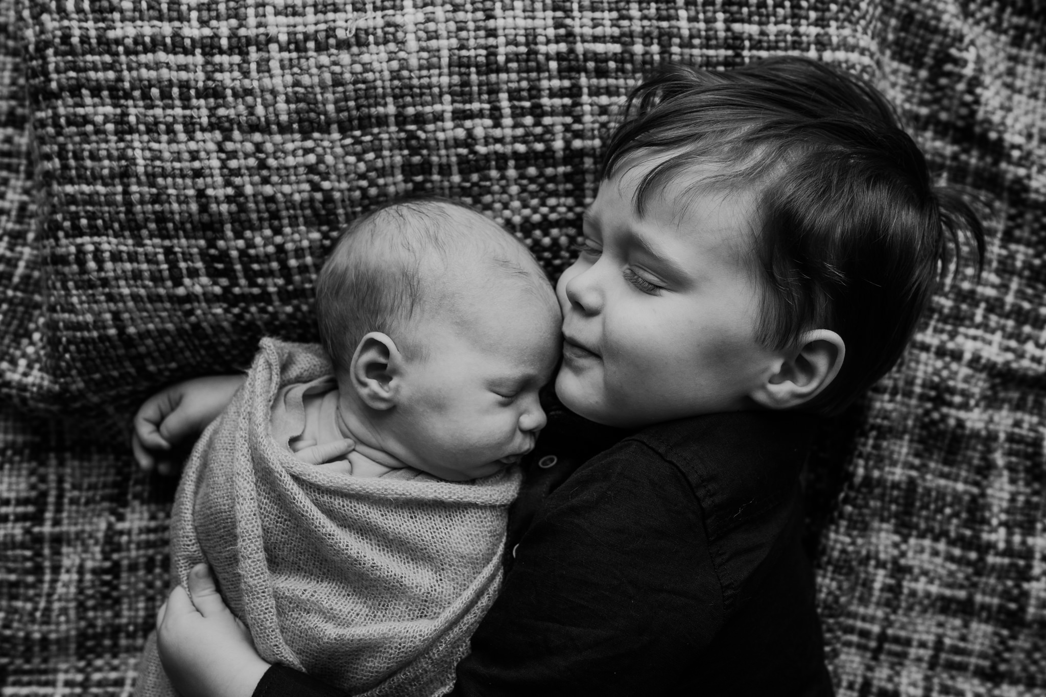 brother hugs newborn sister black and white in home session newborn photographer belfast