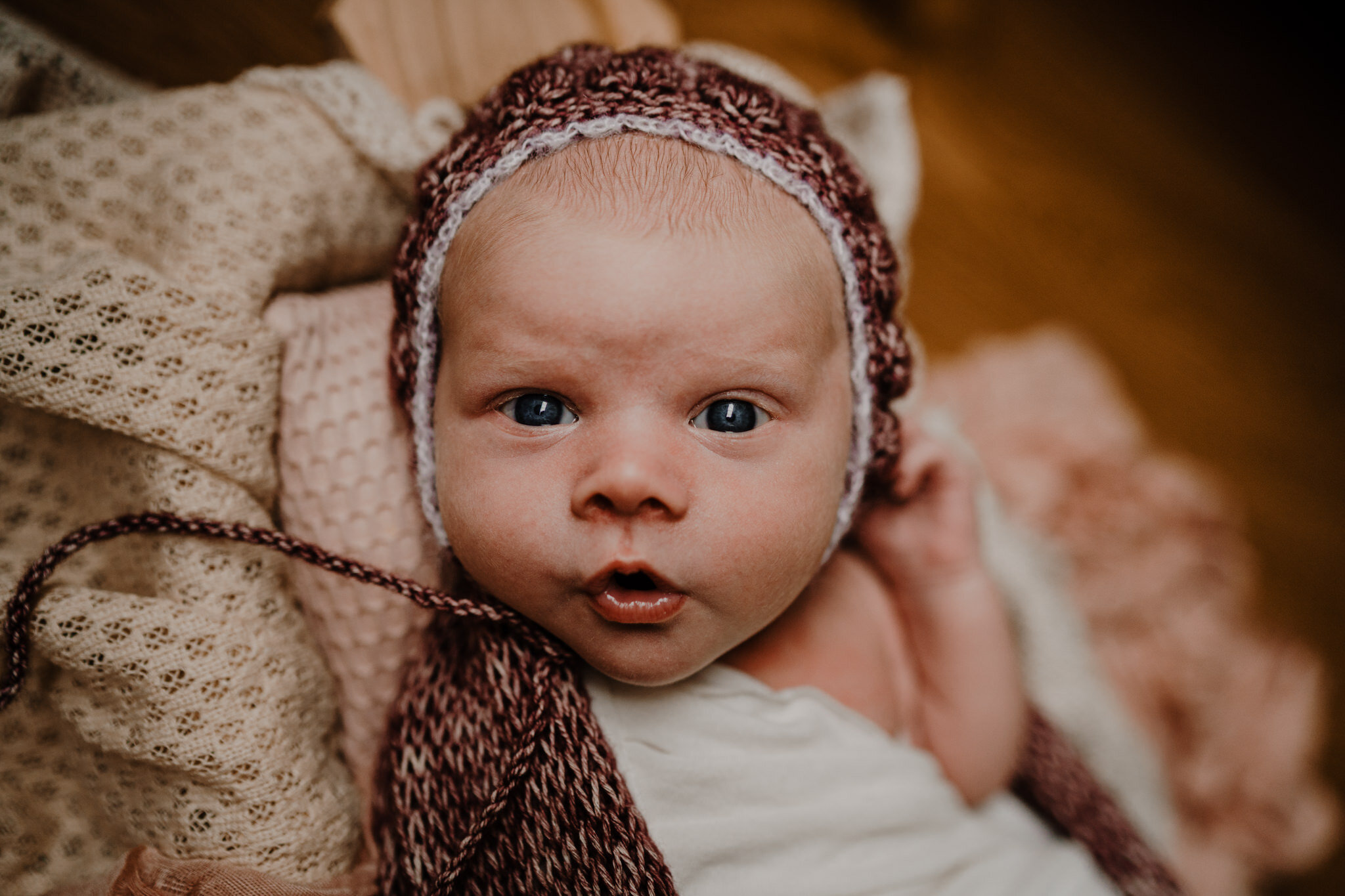 cute expression newborn girl 13 days old raspberry wrap &amp; bonnet in home photography session Belfast