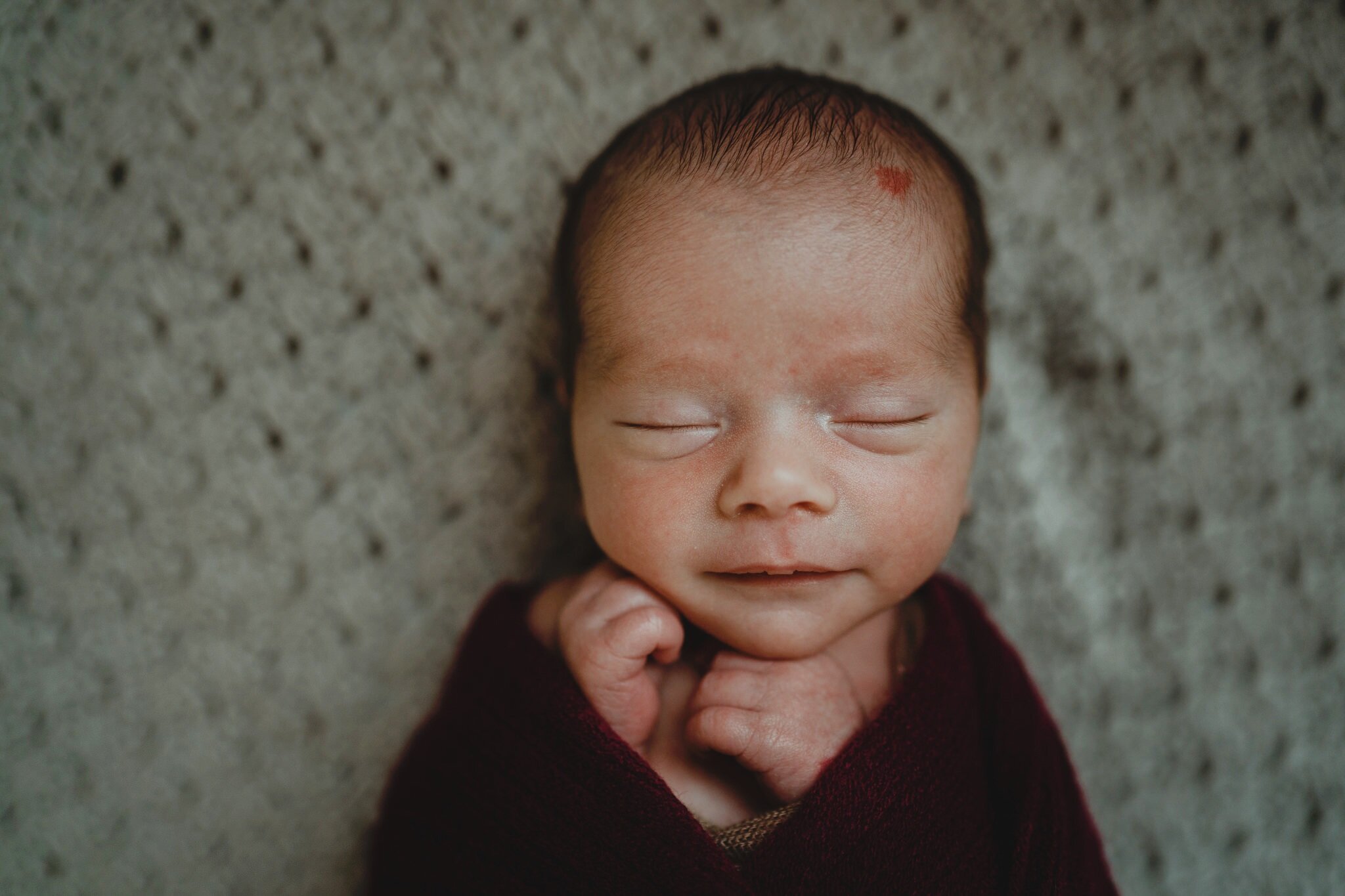 simple grey and burgundy wrap baby boy smiling Newborn Photographer Belfast