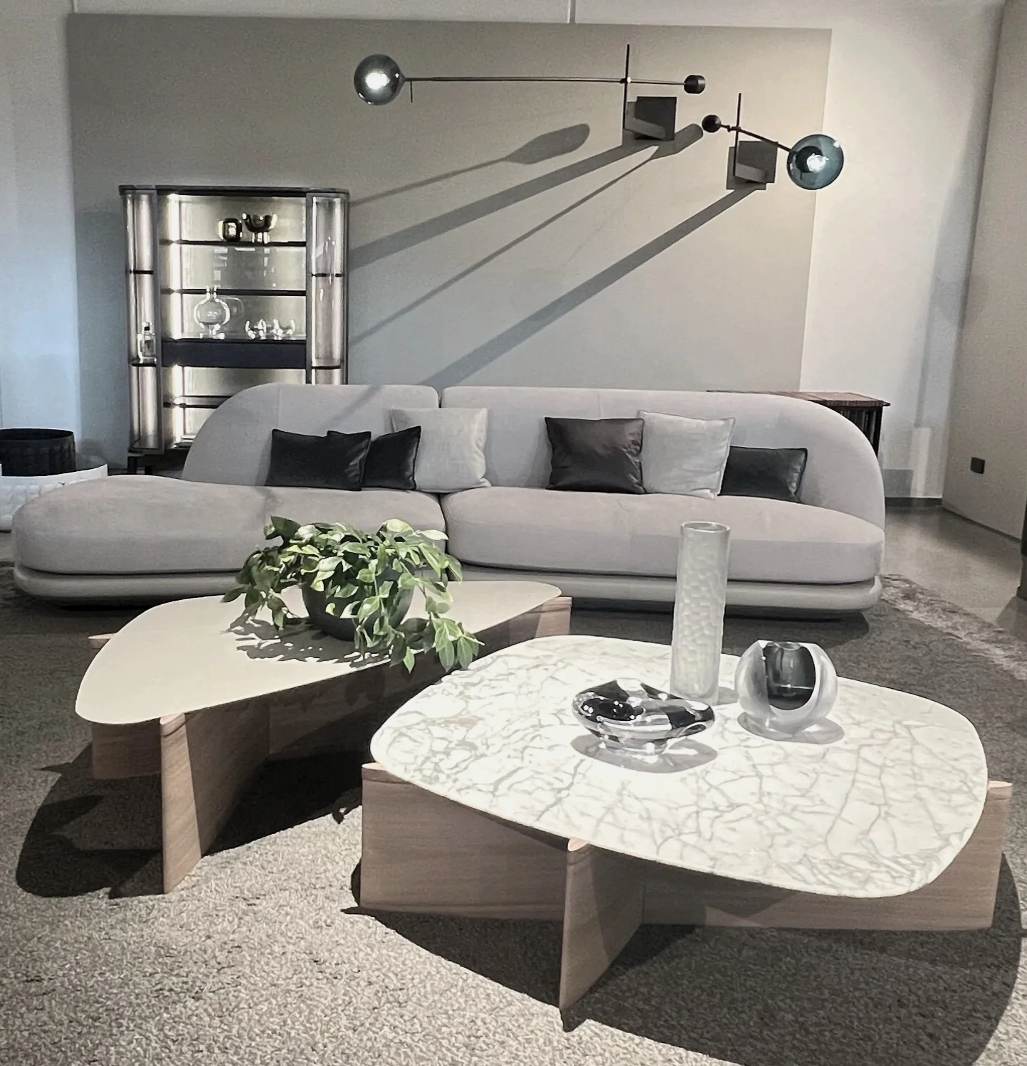 Living room with a white textured sofa, a long striped pillow, a coffee table with decorative vases and magazines, and artwork hanging on the wall.