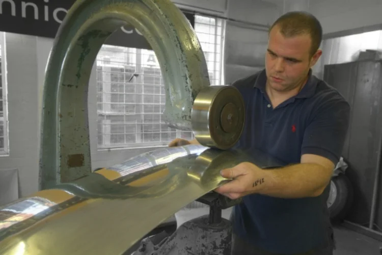 A skilled artisan using an old English wheel to produce a perfectly bespoke piece of bodywork.