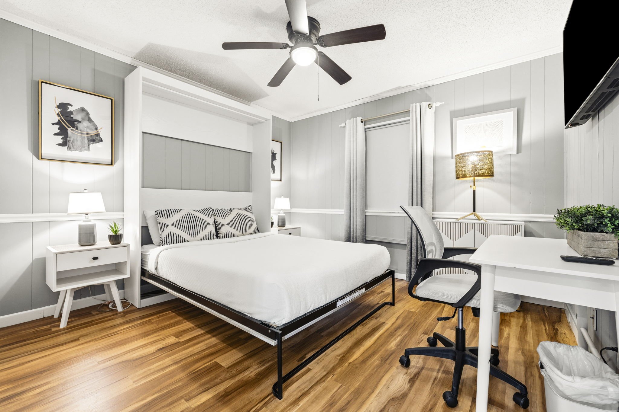 The second bedroom features a comfortable queen bed, calming coastal décor, and a dedicated workspace with desk and chair — perfect for guests who want extra space to relax, work remotely, or unwind after a day at the beach.