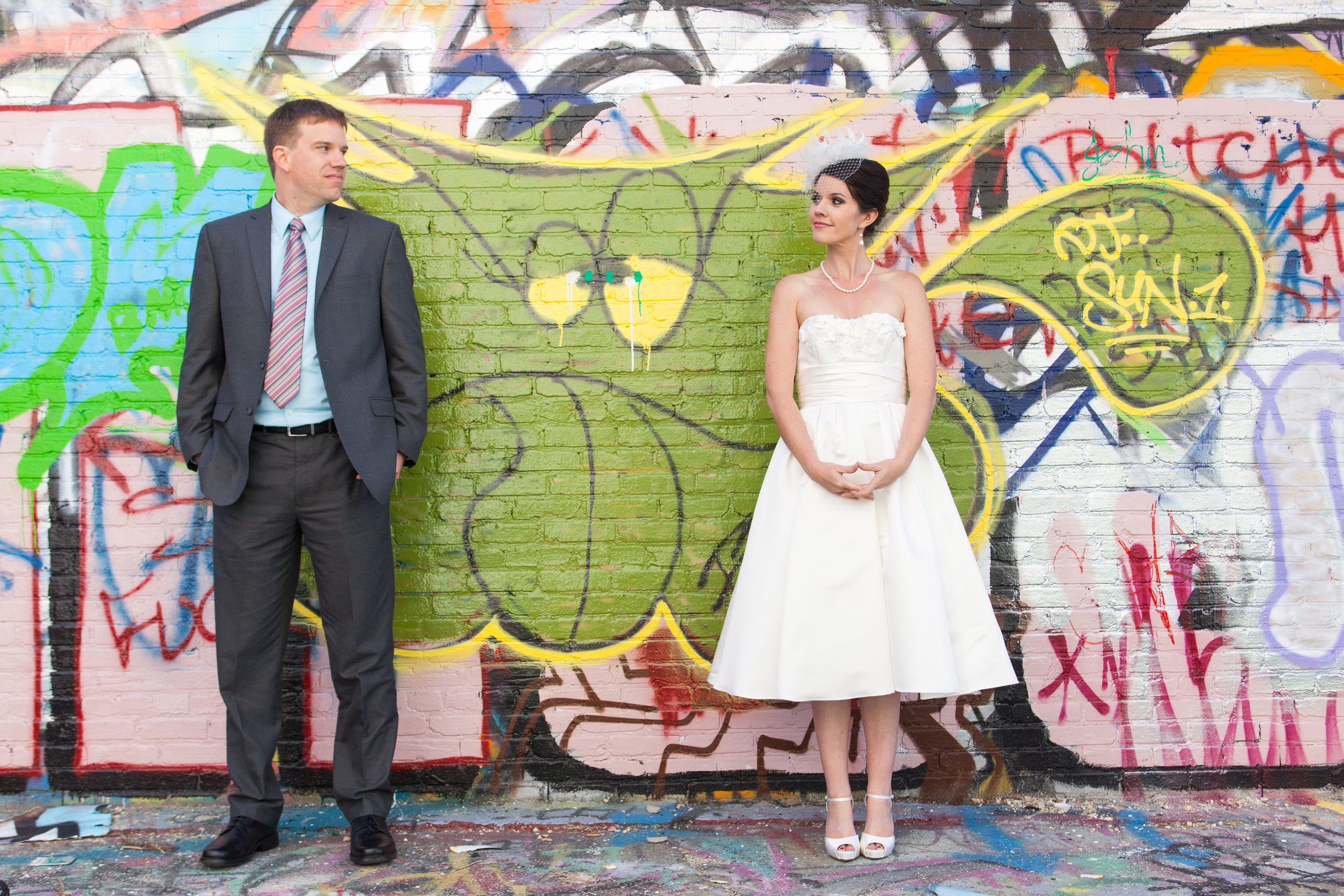 Bride &amp; groom in front of graffiti wall