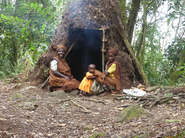 Three Nkoringo natives in front of traditional hut