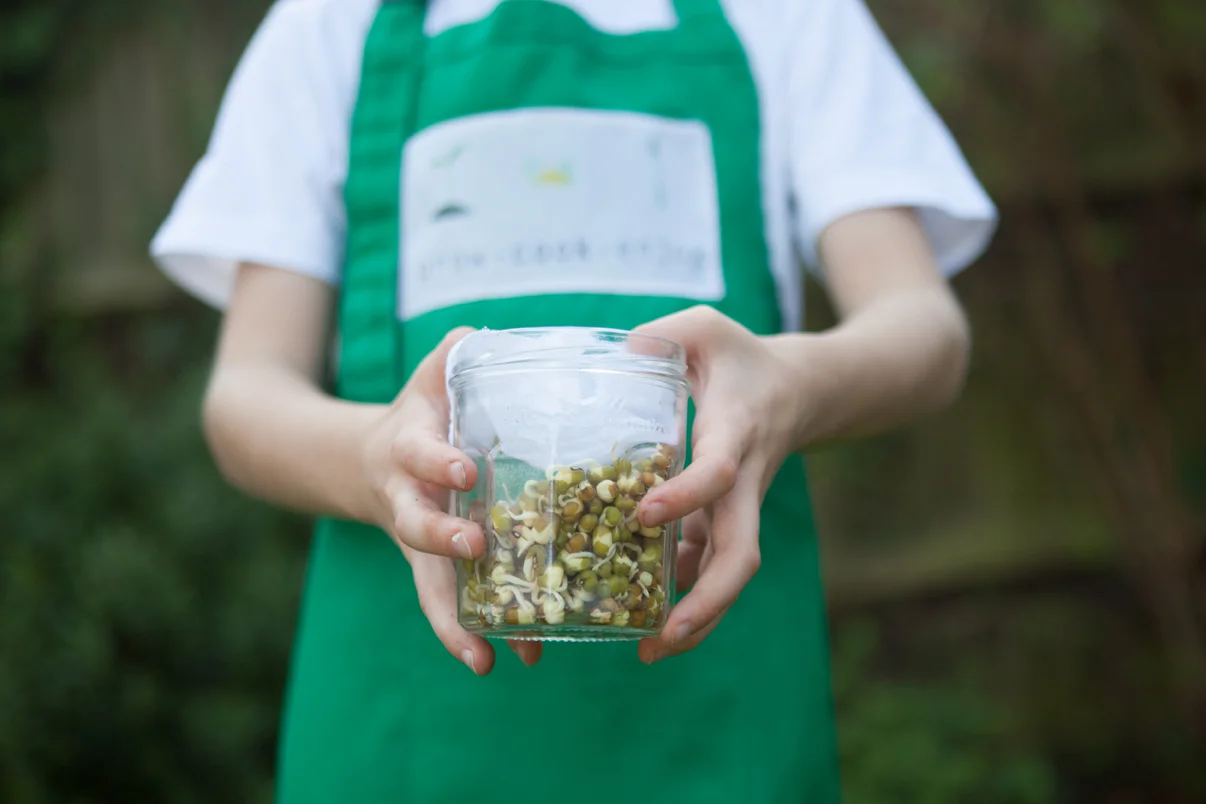 A child holding a jar of sprouted mung beans.
