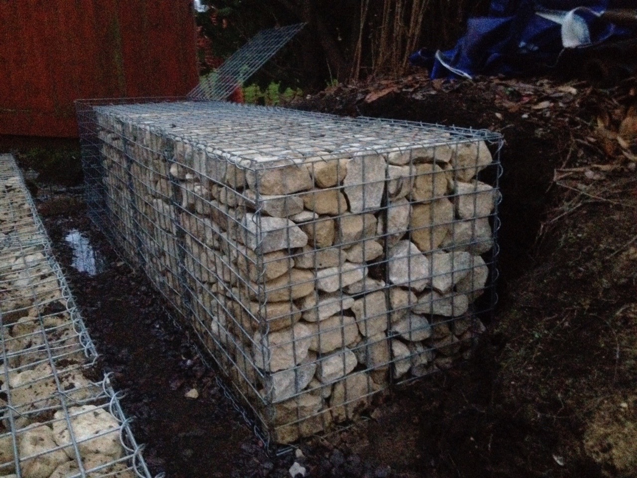 Gabion cages are an excellent retainer for jobs like this. They are incredibly strong and easy to install in difficult areas. Cotswold gabion stone is to fill and locks together inside to give the wire cage strength.